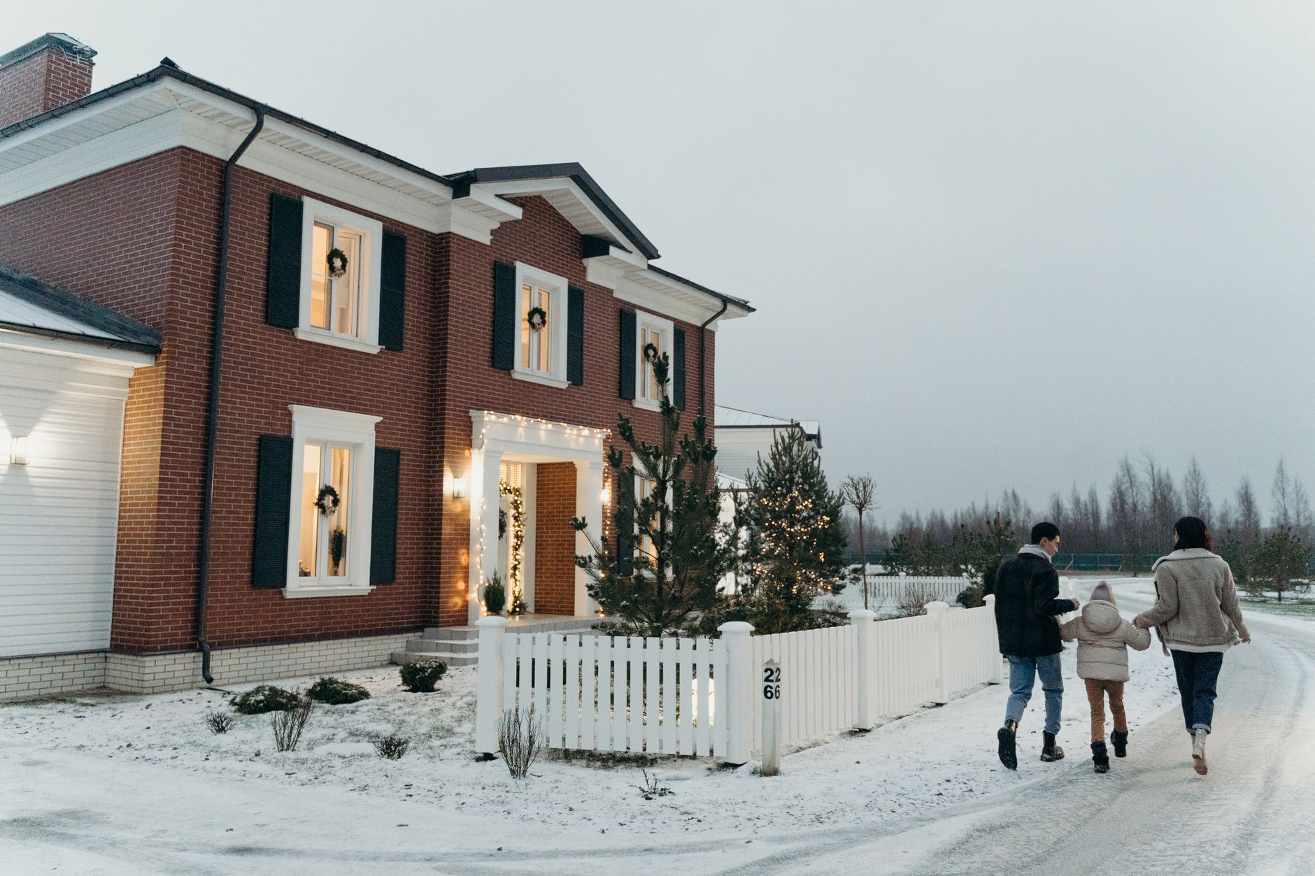 冬日里携手走在雪屋旁的一家人